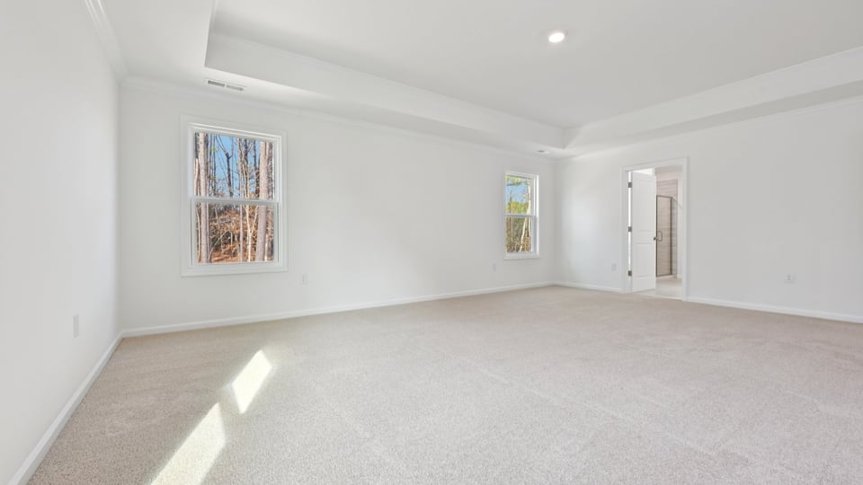 primary bedroom with two windows and carpeting, attached bath