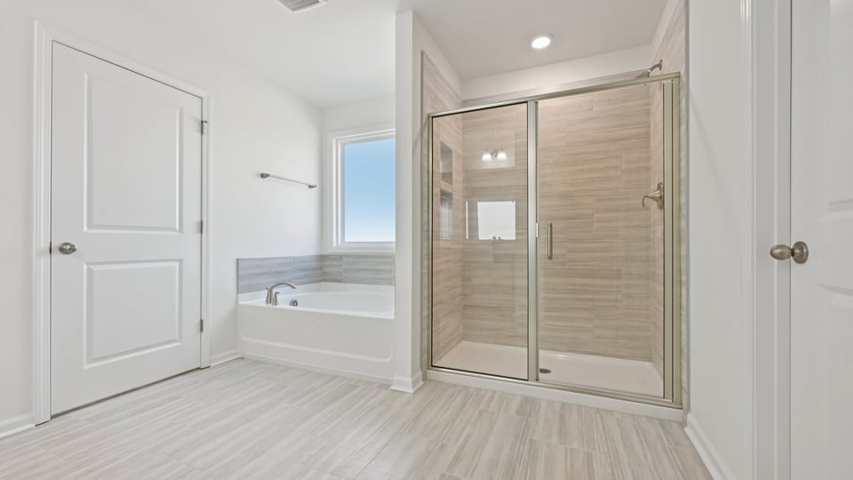 primary bathroom with walk in shower, bathtub, and dual vanity sinks
