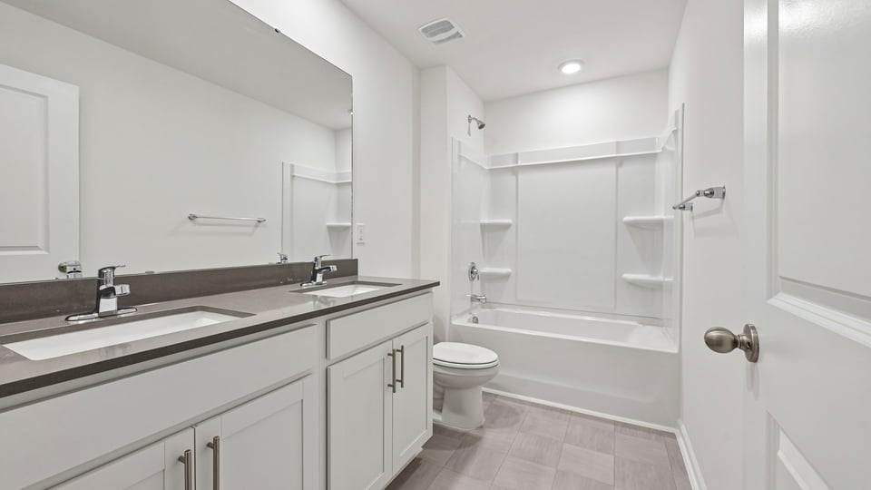 bathroom with dual sinks and tub shower combo