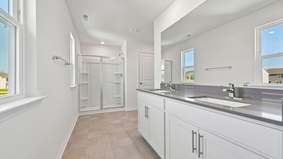 primary bathroom with dual vanity walkin shower and quartz countertops