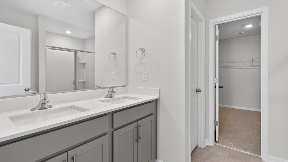 primary bathroom with walk in shower and dual vanity sinks