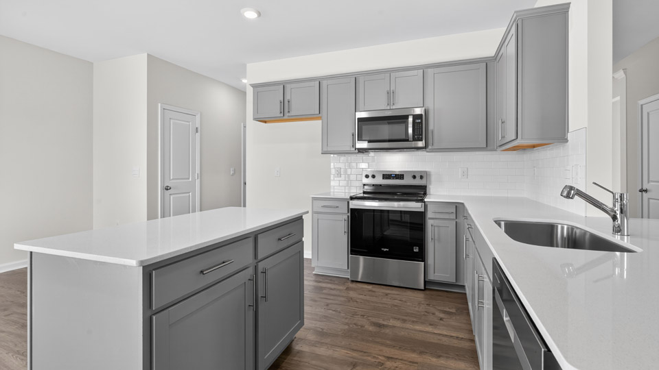 kitchen with quartz counters, kitchen island, pantry, stainless steel appliances