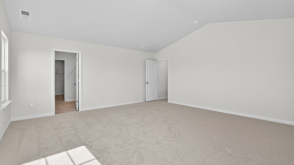 primary bedroom with two windows and carpeting, attached bath