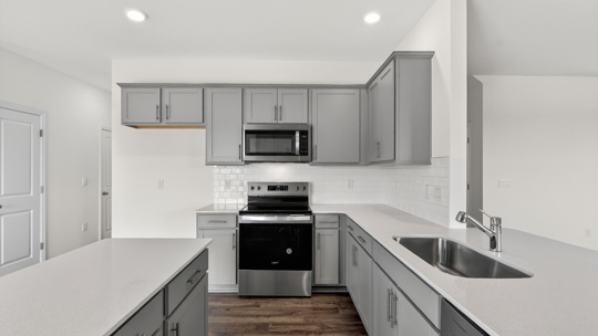 kitchen with quartz counters, kitchen island, pantry, stainless steel appliances