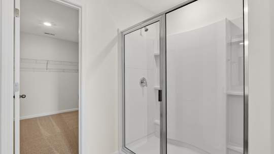 primary bathroom with walk in shower and dual vanity sinks