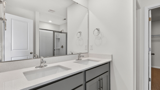 primary bathroom with walk in shower and dual vanity sinks