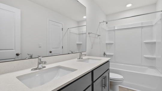 secondary bathroom with shower tub combo and dual vanity sink