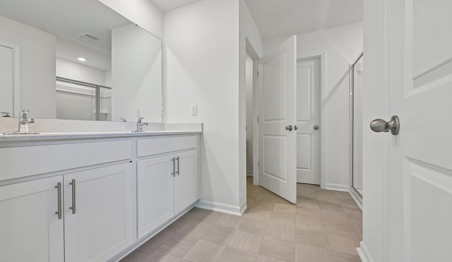 bathroom with dual vanity white cabinets quartz countertops and walkin closet