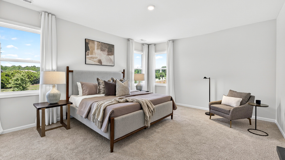primary bedroom with two windows and carpeting, attached bath