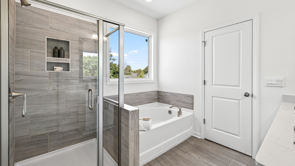 primary bathroom with walk in shower, bathtub, and dual vanity sinks