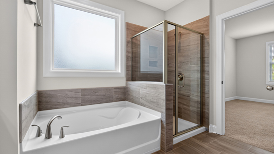 primary bathroom with walk in shower, bathtub, and dual vanity sinks