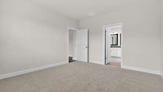 primary bedroom with two windows and carpeting, attached bath