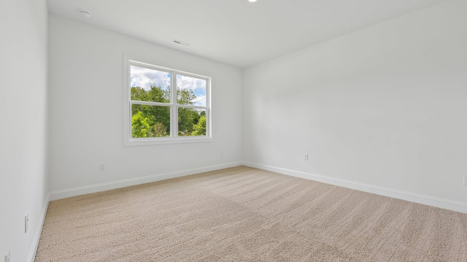primary bedroom with two windows and carpeting, attached bath