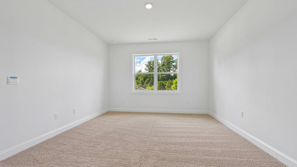 primary bedroom with two windows and carpeting, attached bath