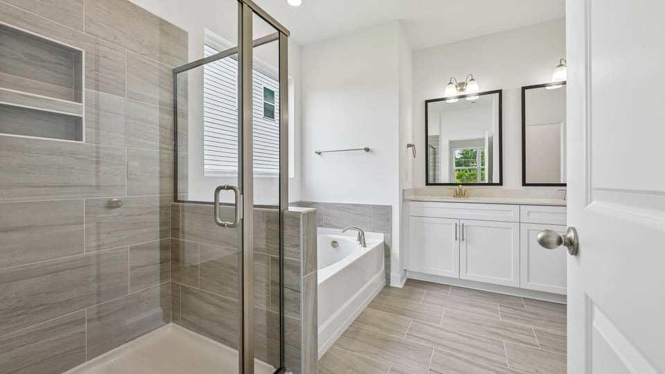 primary bathroom with walk in shower, bathtub, and dual vanity sinks