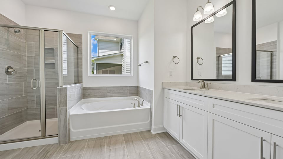 primary bathroom with walk in shower, bathtub, and dual vanity sinks