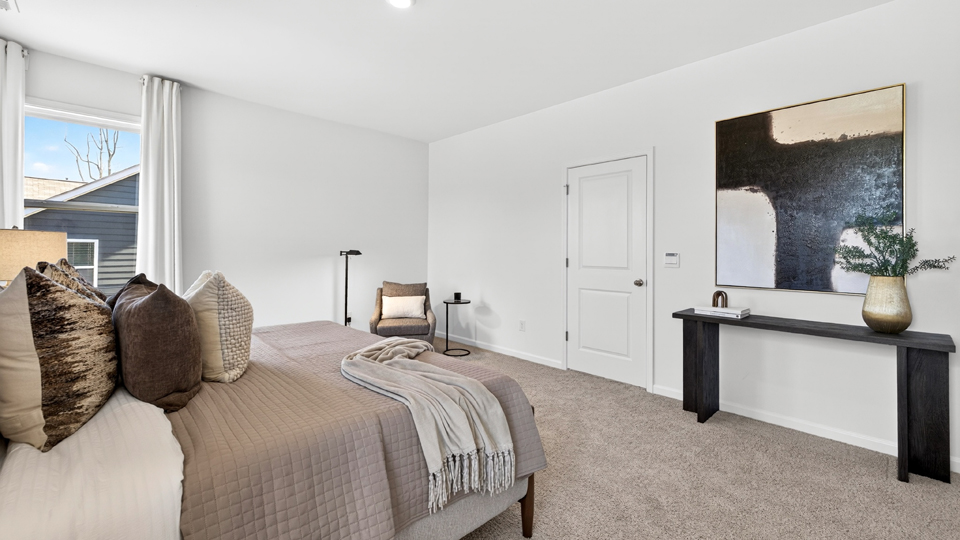 primary bedroom with two windows and carpeting, attached bath