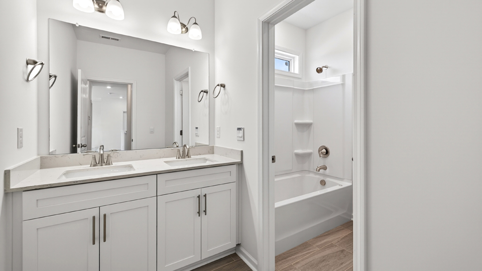 secondary bathroom with shower tub combo and dual vanity sink