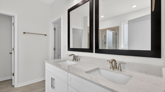 bathroom with dual vanity quartz countertops and white cabinets