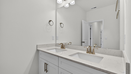 bathroom with dual vanity and quartz countertops