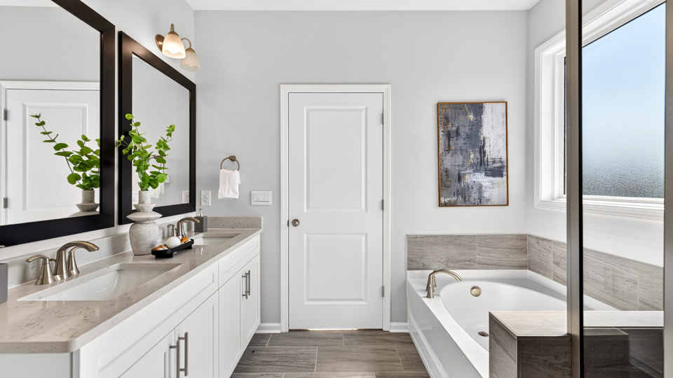 primary bathroom with dual vanity separate tub and walkin shower