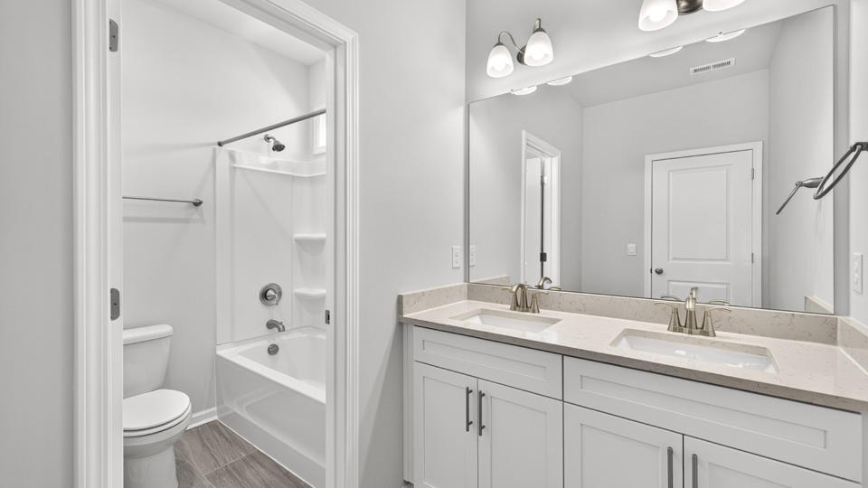 bathroom with dual vanity quartz countertops and white cabinets