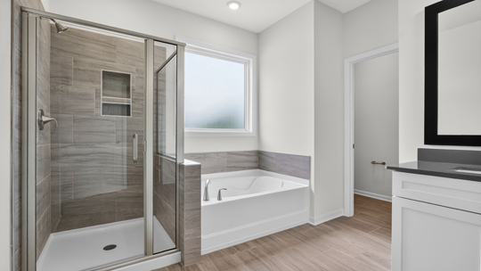 bathroom with dual vanity and separate tub and walk in shower
