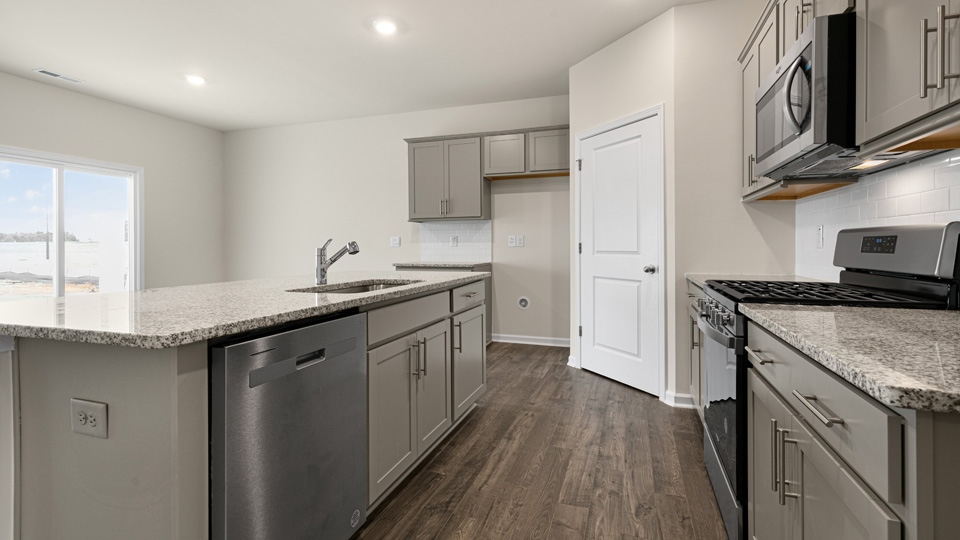 kitchen with quartz counters, kitchen island, pantry, stainless steel appliances