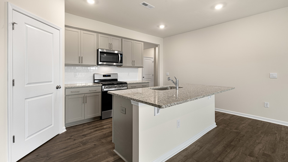 kitchen with quartz counters, kitchen island, pantry, stainless steel appliances