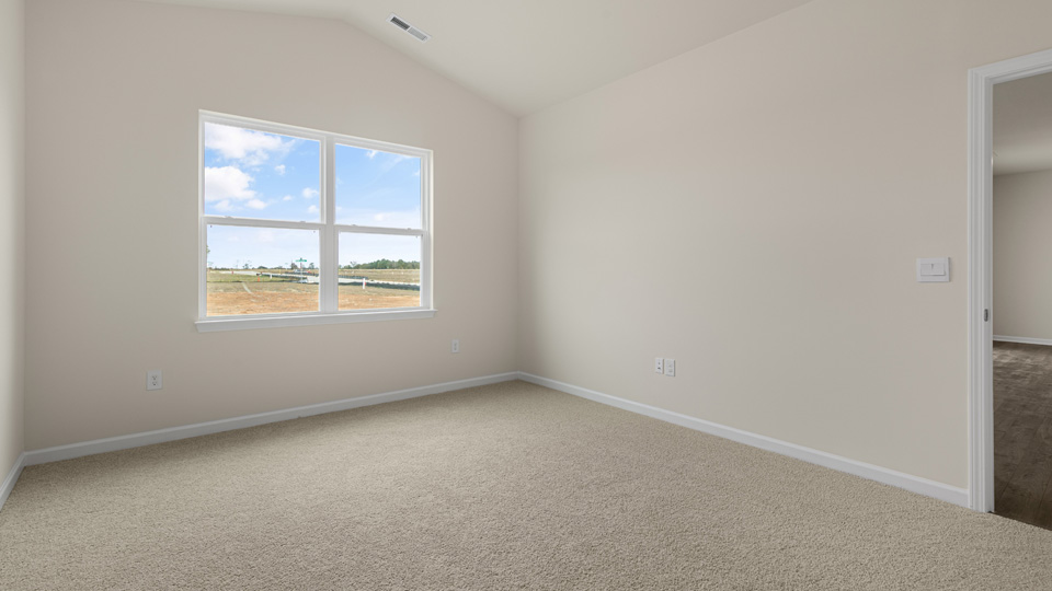 primary bedroom with two windows and carpeting, attached bath