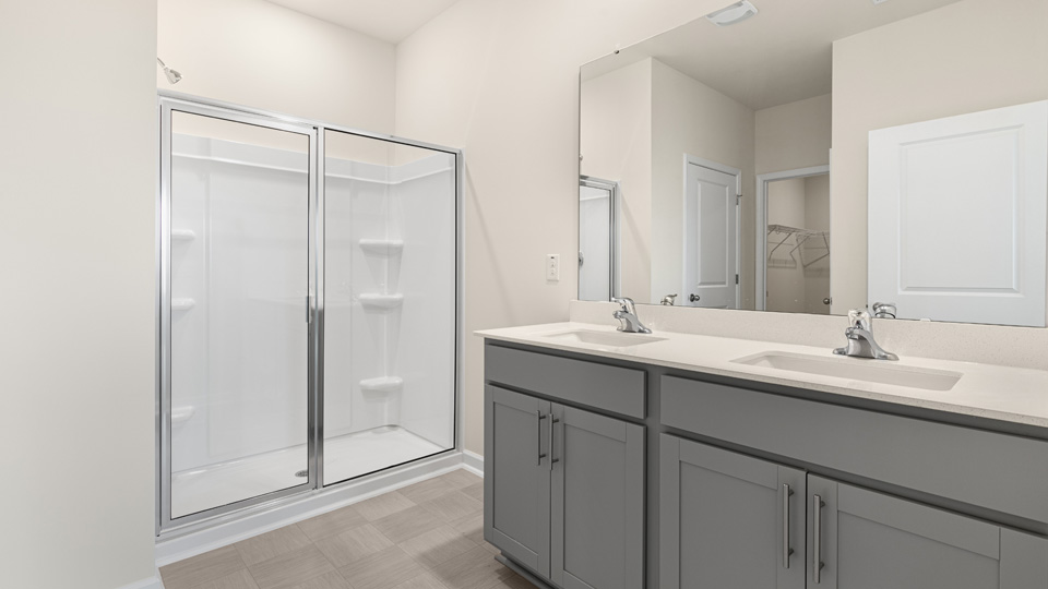 primary bathroom with walk in shower and dual vanity sinks