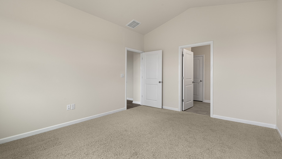 primary bedroom with two windows and carpeting, attached bath