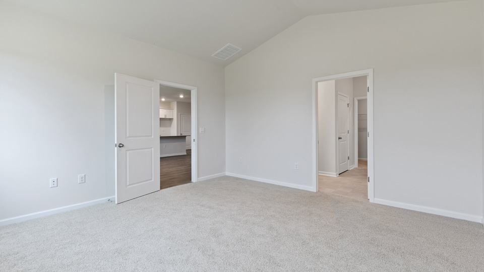 primary bedroom with two windows and carpeting, attached bath