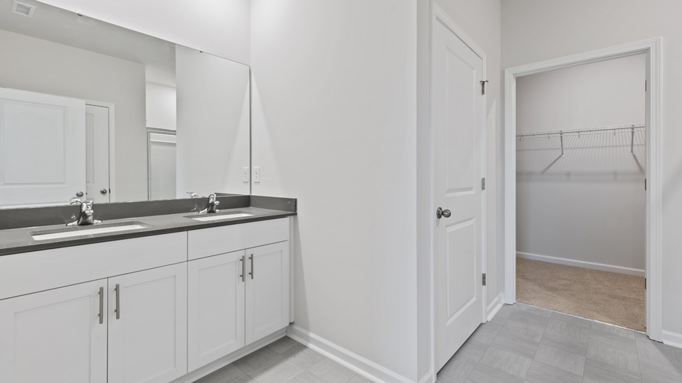 primary bathroom with walk in shower and dual vanity sinks