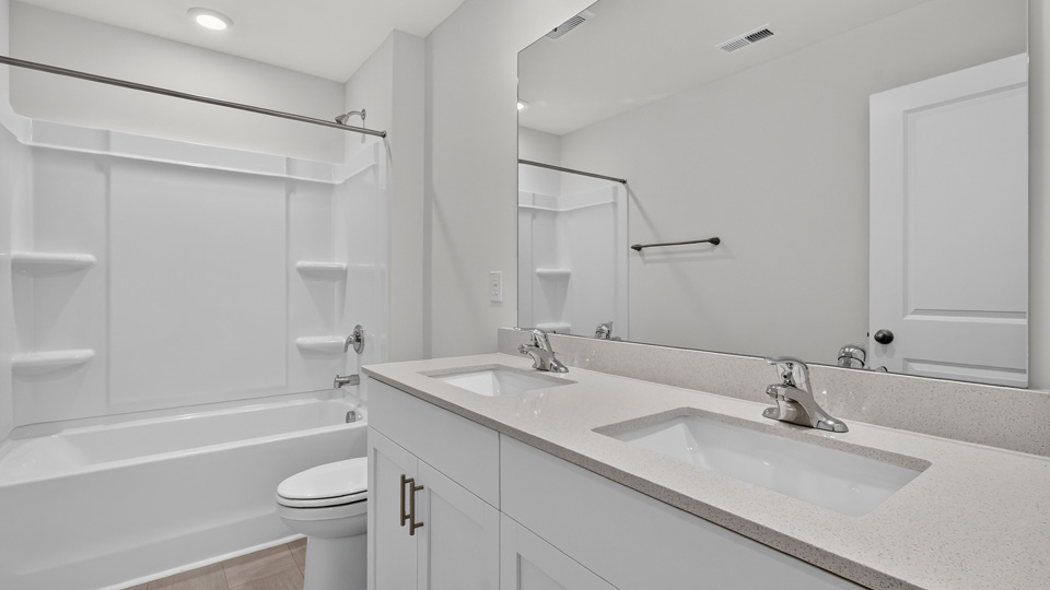 secondary bathroom with shower tub combo and dual vanity sink