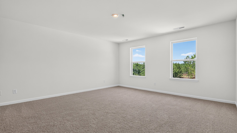 primary bedroom with two windows and carpeting, attached bath