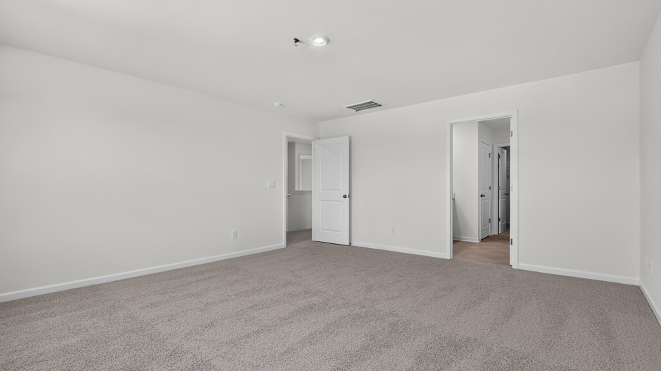 primary bedroom with two windows and carpeting, attached bath