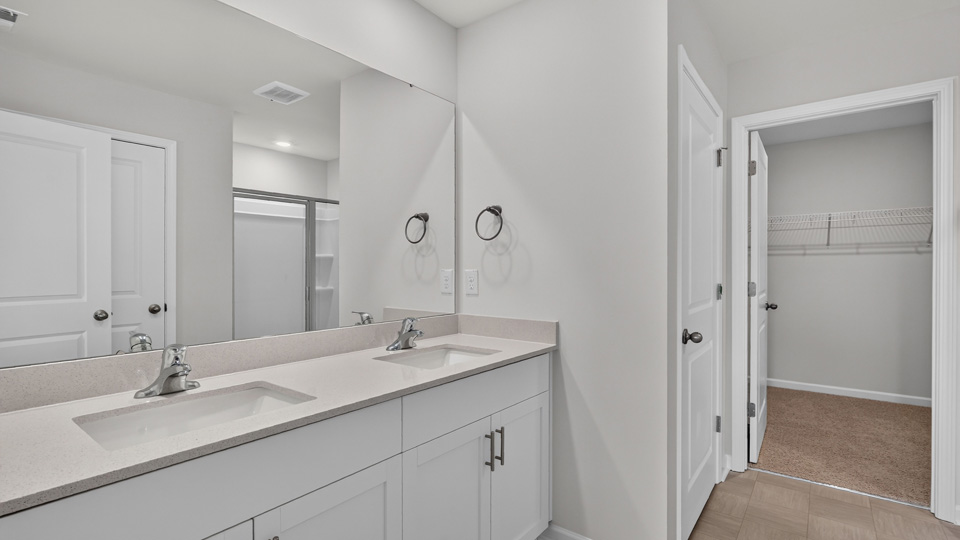 primary bathroom with walk in shower and dual vanity sinks
