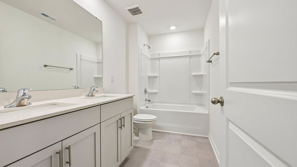 bathroom with dual vanity quartz countertops and tub shower combo