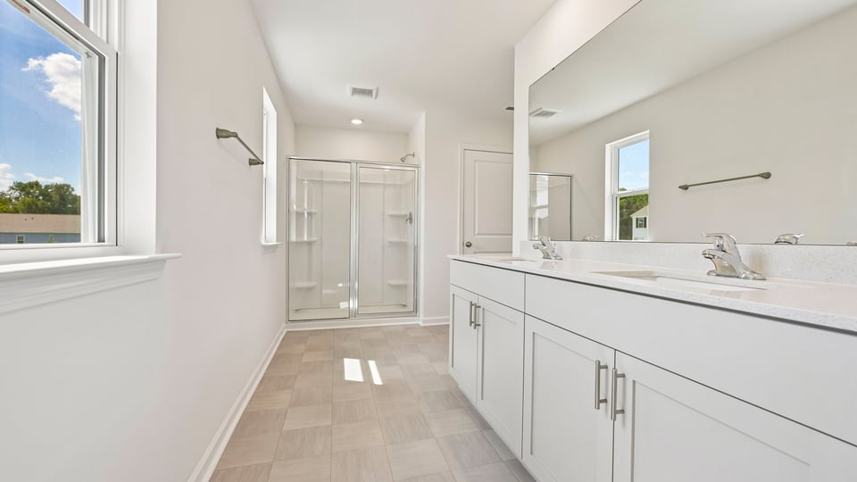 primary bathroom with dual vanity and walkin glass door shower
