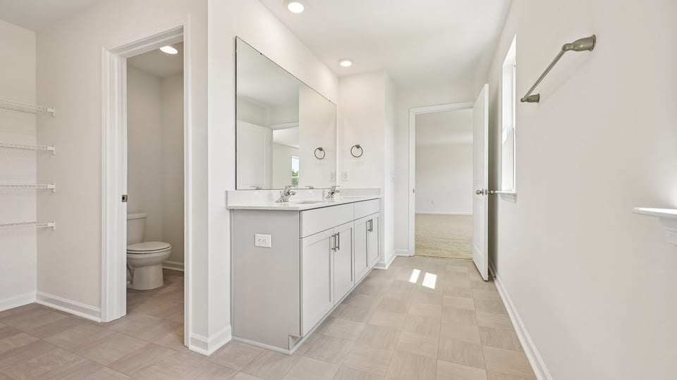 primary bathroom with water closet and quartz countertops