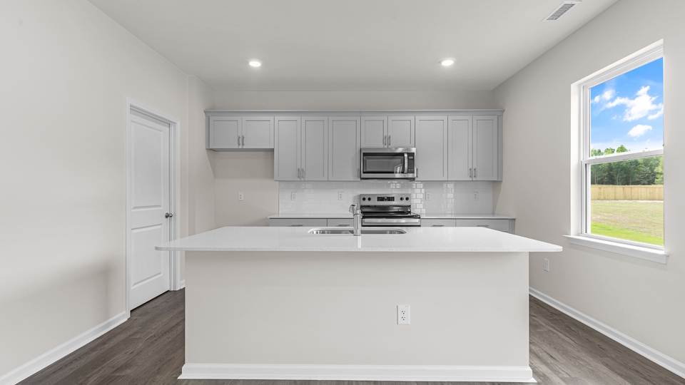 kitchen with quartz counters, kitchen island, pantry, stainless steel appliances