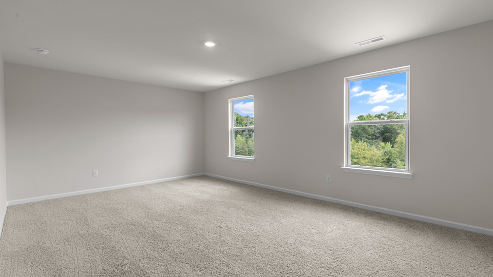 primary bedroom with two windows and carpeting, attached bath
