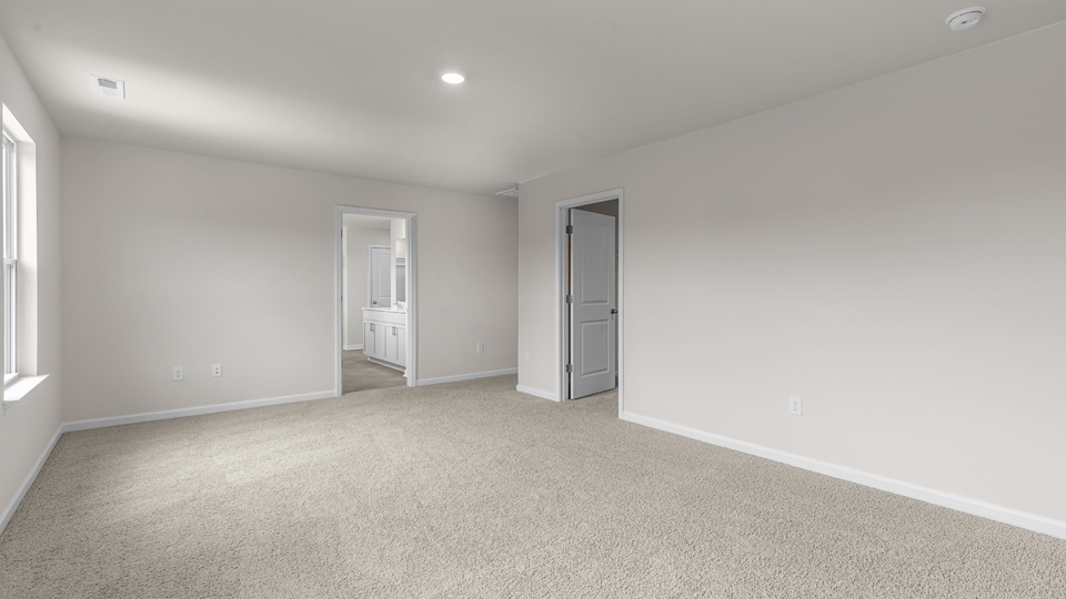 primary bedroom with two windows and carpeting, attached bath