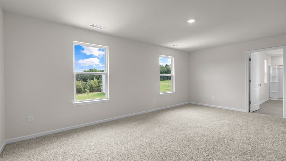 primary bedroom with two windows and carpeting, attached bath