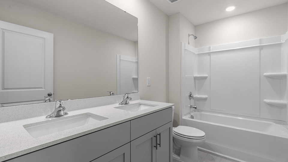 secondary bathroom with shower tub combo and dual vanity sink