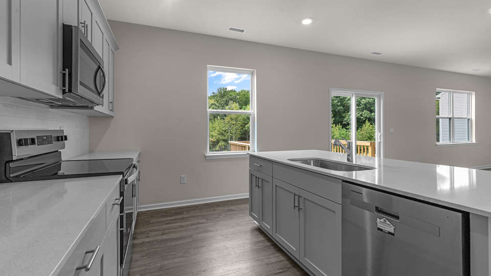 kitchen with quartz counters, kitchen island, pantry, stainless steel appliances
