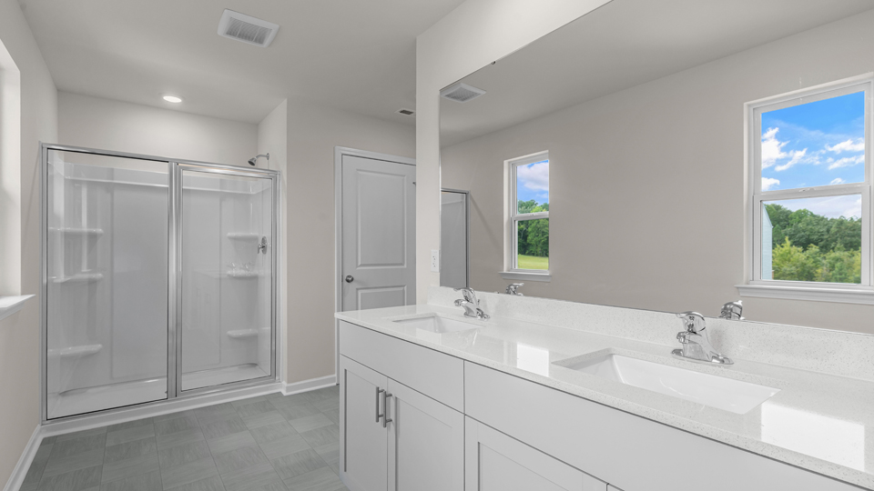 primary bathroom with walk in shower and dual vanity sinks