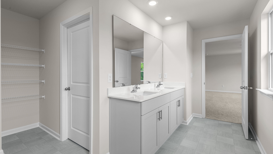 primary bathroom with walk in shower and dual vanity sinks