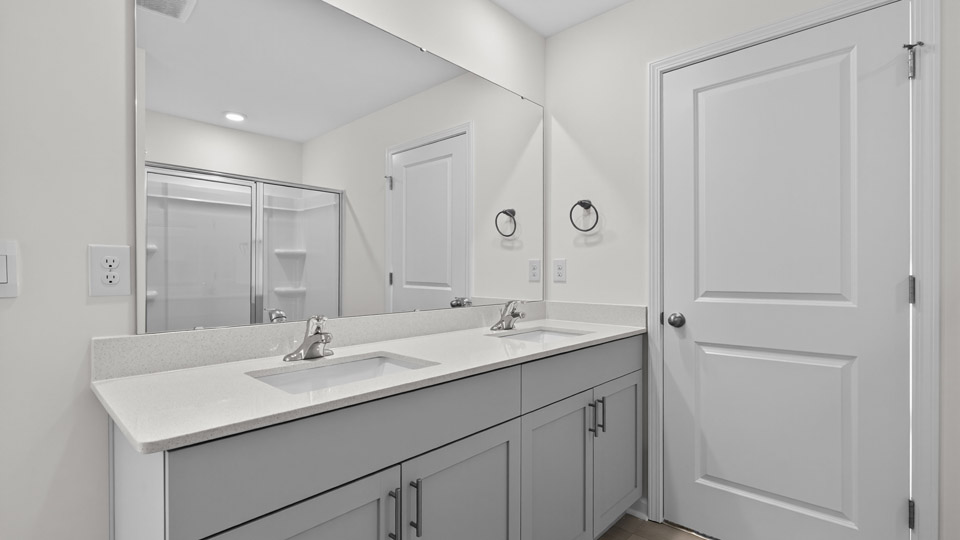 primary bathroom with walk in shower and dual vanity sinks